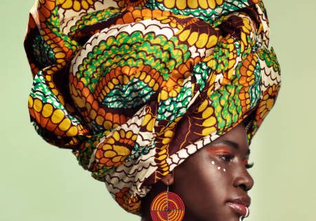 Studio shot of a beautiful young woman wearing a traditional African head wrap against a green background