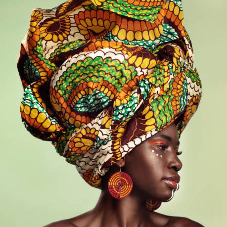 Studio shot of a beautiful young woman wearing a traditional African head wrap against a green background